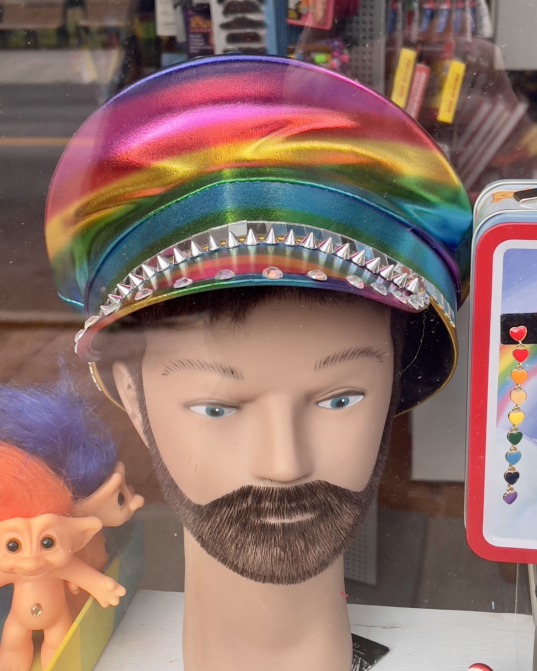 Gay pride hat on bearded male bust in local shop window.