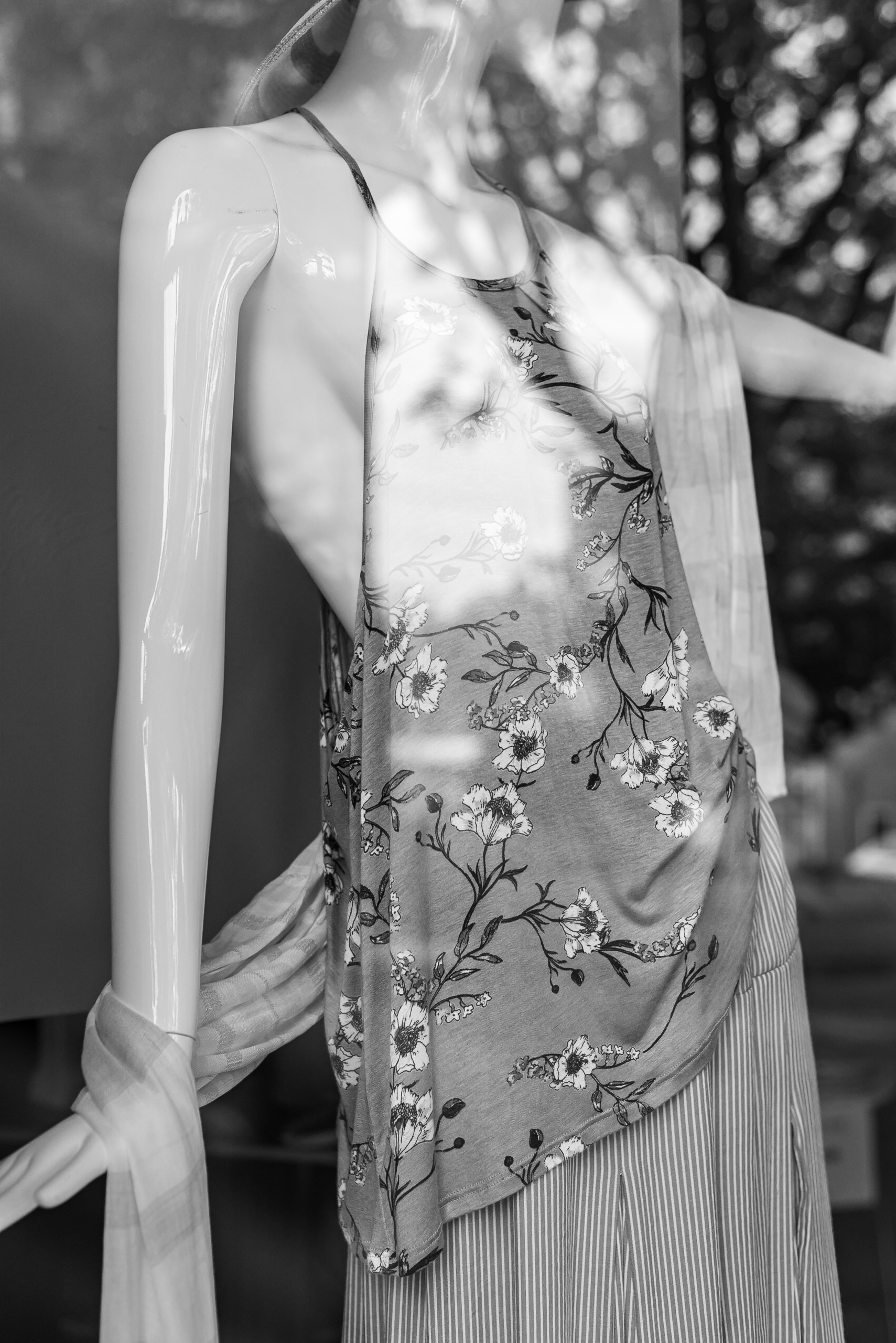Shop mannequin wearing a floral, loosely draped, halter top and thinly stripped skirt.
