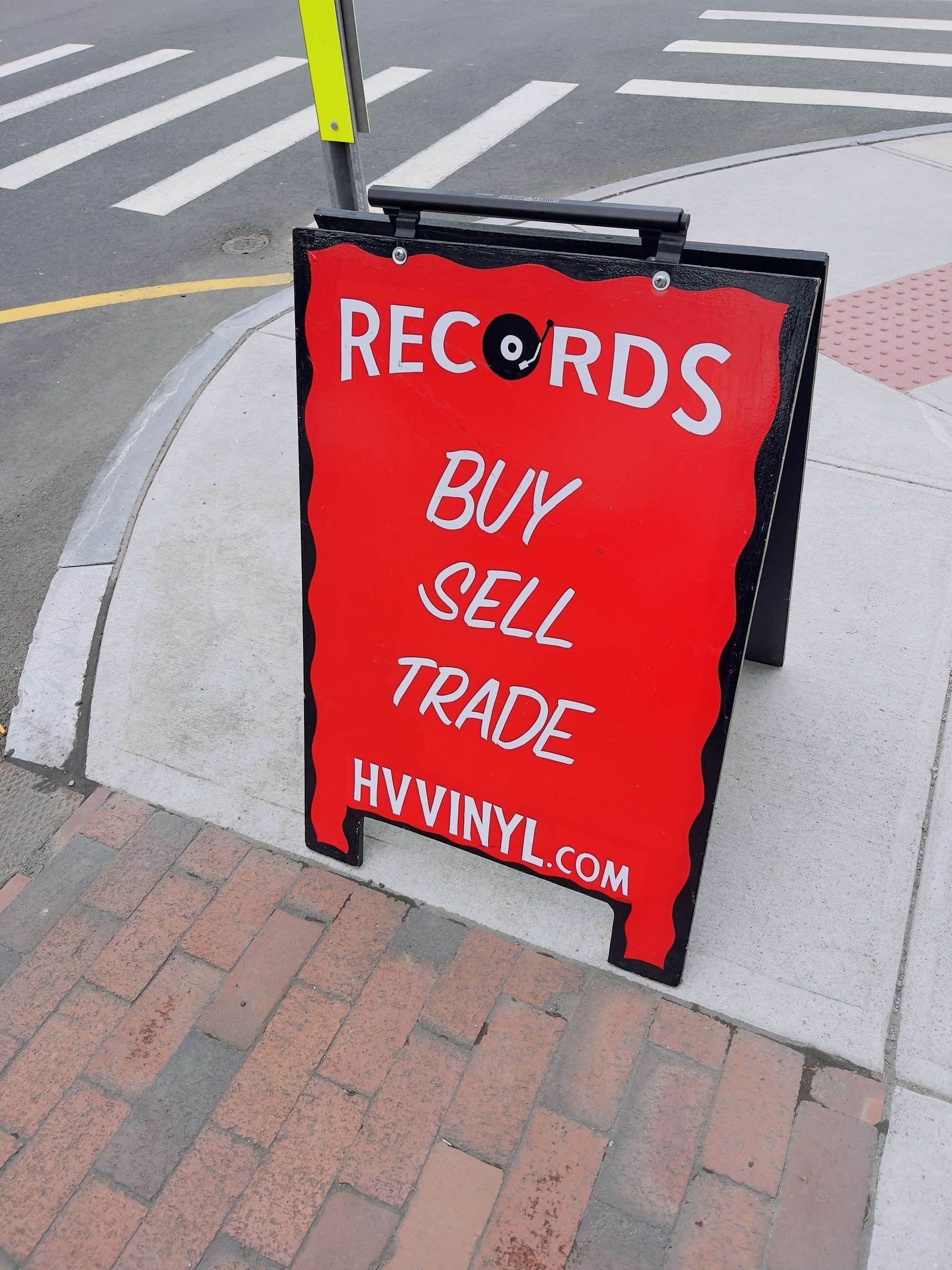 Sandwich board outside local vinyl records store saying “Records, by, sell, trade, hvvinyl.com”